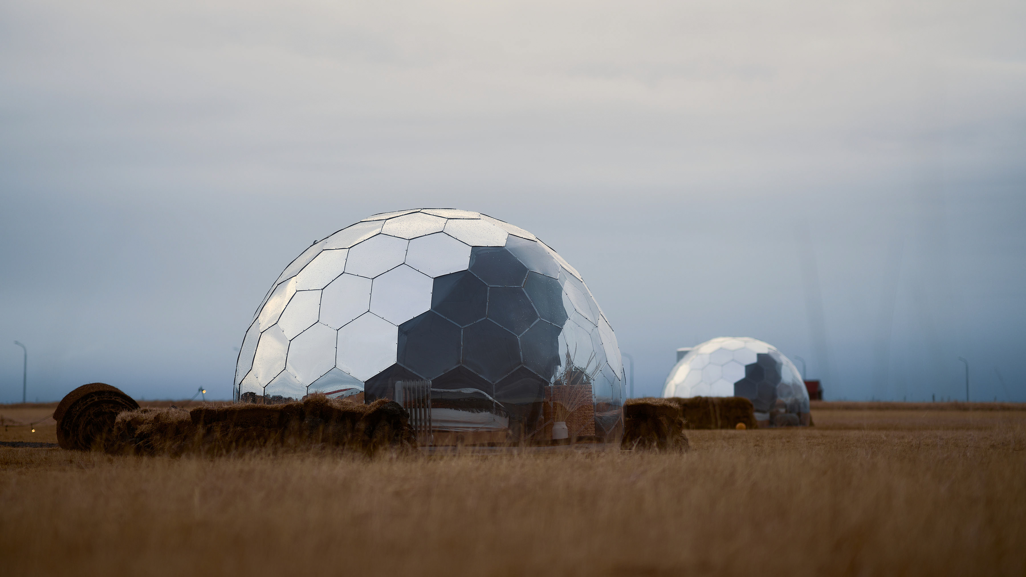 Mirror geodome in forest meadow at sunset glamping setting